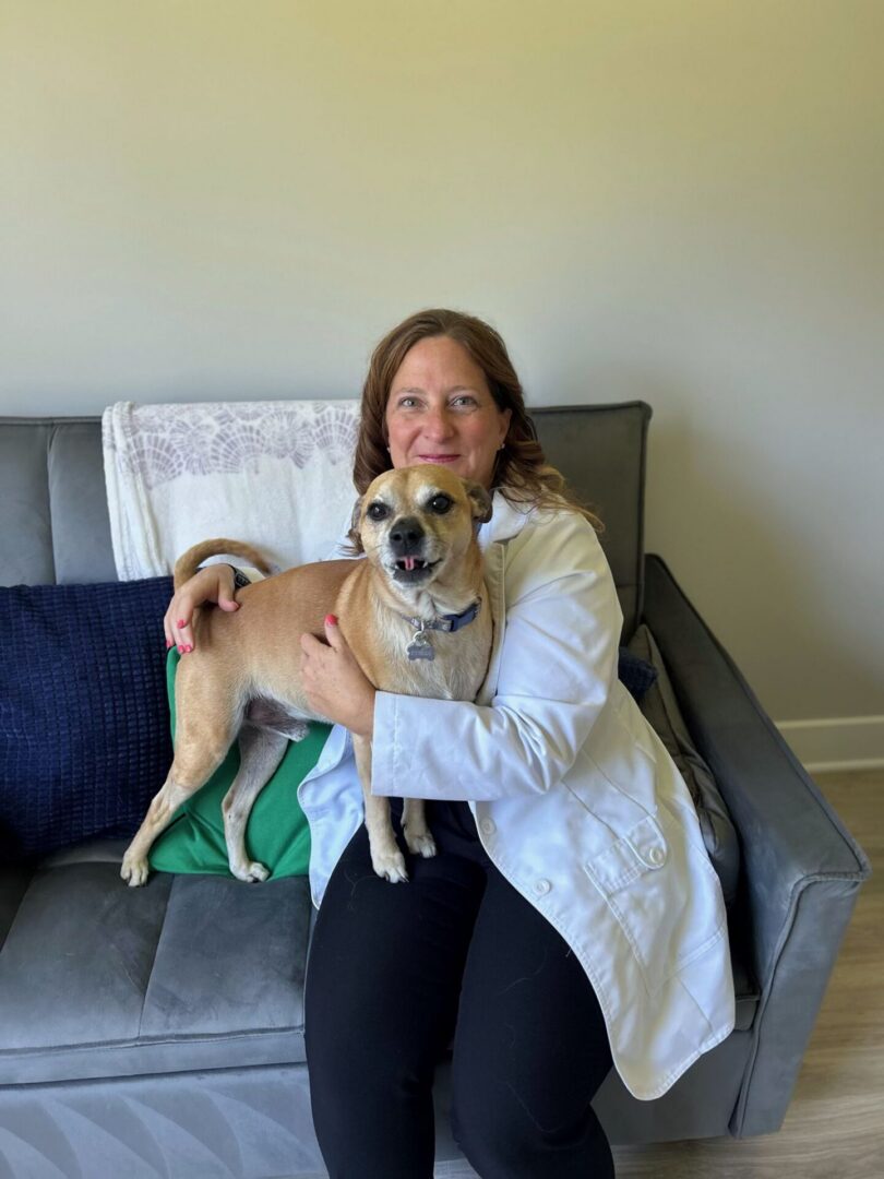 A woman and a dog sitting on a sofa.